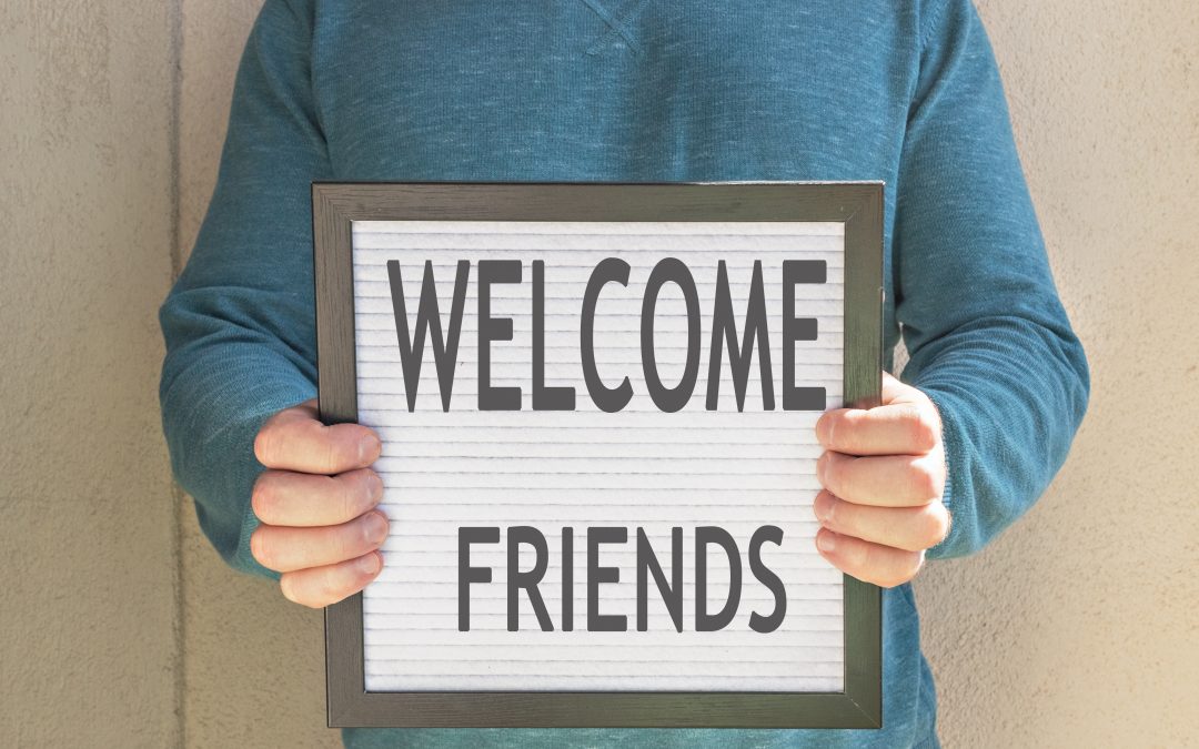 A man holding a sign that states "Welcome Friends"